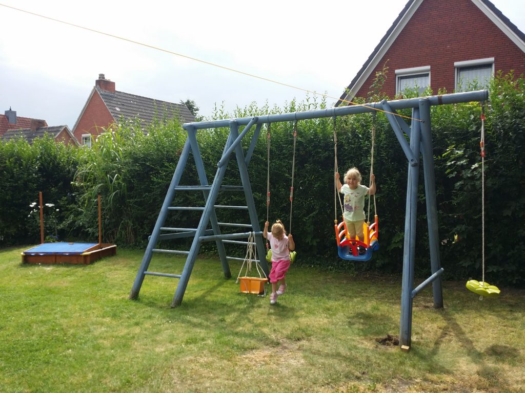 Kinder haben Spaß beim Klettern, Schaukeln und im Sandkasten